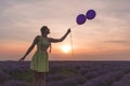 A beautiful model with long braids stands in a lavender field. Holds two balloons in his hands. Sunset in the background Royalty Free Stock Photo