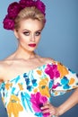 Beautiful model with updo hair and perfect bright make up wearing colorful open shoulder dress with floral print and peony garland Royalty Free Stock Photo