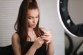 Beautiful model use the phone during the break. ring lamp. Portrait of young attractive woman with beutiful makeup in Royalty Free Stock Photo