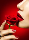 Beautiful model woman kissing red rose flower