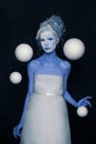 Beautiful model woman with stage makeup and hairstyle standing with white planet spheres on black background. Royalty Free Stock Photo