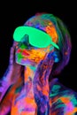 Beautiful model woman wearing glasses with colorful bright fluorescent makeup in neon light, nightclub disco Royalty Free Stock Photo