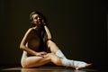 Beautiful modern ballet dancer with perfect body sits on the floor in the studio hall. Royalty Free Stock Photo