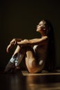 Beautiful modern ballet dancer with perfect body sits on the floor in the studio hall. Royalty Free Stock Photo