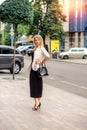 Beautiful modern blonde girl in a black dress and an oatmeal jacket Royalty Free Stock Photo