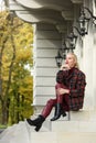 A beautiful, modern, fashionable blonde girl with a red lipstick posing outdoors . red leather leggings, turtleneck and Royalty Free Stock Photo