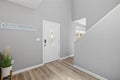 Beautiful and modern foyer with light wood floors and a white door leading to the upstairs staircase