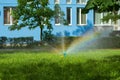 Beautiful modern houses painted in bright colors.Beautiful blue sky and clouds.Auto-watering system and rainbow in jets of water Royalty Free Stock Photo