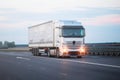 A beautiful modern semi-trailer truck drives along the highway in the morning with fog lights on during fog