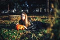 Beautiful modern witch holding halloween pumpkin in the forest. october. happy holidays