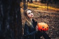 Beautiful modern witch holding halloween pumpkin in the forest. october. happy holidays