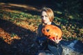 Beautiful modern witch holding halloween pumpkin in the forest. october. happy holidays