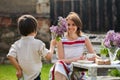 Beautiful mom, having coffee in a backyard, young cute child giving her present and flowers Royalty Free Stock Photo