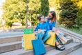 Beautiful mom and her cute little daughter are holding shopping bags, looking at camera and smiling while standing outdoors. Royalty Free Stock Photo