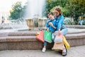 Beautiful mom and her cute little daughter are holding shopping bags, looking at camera and smiling while standing outdoors. Royalty Free Stock Photo