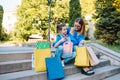 Beautiful mom and her cute little daughter are holding shopping bags, looking at camera and smiling while standing outdoors. Royalty Free Stock Photo