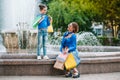 Beautiful mom and her cute little daughter are holding shopping bags, looking at camera and smiling while standing outdoors. Royalty Free Stock Photo