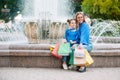 Beautiful mom and her cute little daughter are holding shopping bags, looking at camera and smiling while standing outdoors. Royalty Free Stock Photo