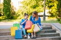 Beautiful mom and her cute little daughter are holding shopping bags, looking at camera and smiling while standing outdoors. Royalty Free Stock Photo