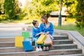 Beautiful mom and her cute little daughter are holding shopping bags, looking at camera and smiling while standing outdoors. Royalty Free Stock Photo