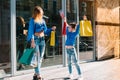 Beautiful mom and her cute little daughter are holding shopping bags, looking at camera and smiling while standing outdoors. Royalty Free Stock Photo