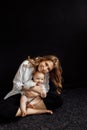 Beautiful mom is sitting in the studio and holding her little daughter, looking at the camera, smiling. Beautiful young Royalty Free Stock Photo