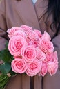 Beautiful mono bouquet of pink roses. Woman in brown coat holding bouquet of roses. Royalty Free Stock Photo