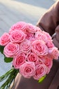 Beautiful mono bouquet of pink roses. Woman in brown coat holding bouquet of roses. Royalty Free Stock Photo