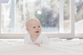 Beautiful 6 Month Baby Boy Dressed in White & Lying on Fluffy White Blanket Looking at Camera. Smiling & Happy Royalty Free Stock Photo