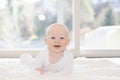 Beautiful 6 Month Baby Boy Dressed in White & Lying on Fluffy White Blanket Looking at Camera. Smiling & Happy Royalty Free Stock Photo