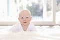 Beautiful 6 Month Baby Boy Dressed in White & Lying on Fluffy White Blanket Looking at Camera. Smiling & Happy Royalty Free Stock Photo