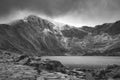 Beautiful moody Winter landscape image of Llyn Idwal and snowcapped Glyders Mountain Range in Snowdonia in black and white
