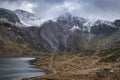 Beautiful moody Winter landscape image of Llyn Idwal and snowcapped Glyders Mountain Range in Snowdonia