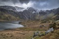 Beautiful moody Winter landscape image of Llyn Idwal and snowcapped Glyders Mountain Range in Snowdonia