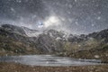 Beautiful moody Winter landscape image of Llyn Idwal and snowcapped Glyders Mountain Range in Snowdonia