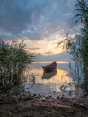 Beautiful morning landscape with a boat on the lake at the sunrise through the reed