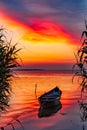 Beautiful morning landscape with a boat on the lake at the sunrise through the reed