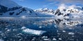 Antarctica, panoramic scenery with snowcapped mountains reflecting in blue water with ice flows, Lemaire Channel near Paradise Bay