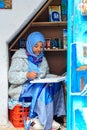 A beautiful Moroccan girl, a Muslim, street artist paints a picture with a brush in a small workshop
