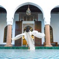 Beautiful Moroccan Girl Waving her white mantle in Rich interior of Picturesque Dar Si Said Riyad in Marrakech