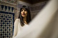 Beautiful Moroccan Girl in white mantle cloak in Rich interior of Picturesque Dar Si Said Riyad in Marrakech