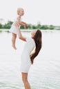 Beautiful mother with baby daughter are having fun and playing near the lake. The concept of summer holiday. Mother`s Royalty Free Stock Photo