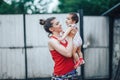 Beautiful Mother And Baby outdoors on the yard of house. Beauty Mum and her baby Child one year old playing in yard together. Mom Royalty Free Stock Photo