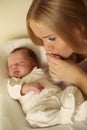 Beautiful mother with blond hair kissing her newborn baby Royalty Free Stock Photo