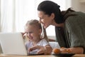 Mother daughter looking at laptop screen spend time in kitchen Royalty Free Stock Photo