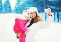 Beautiful mother and child makes photo self-portrait on the smartphone in the winter