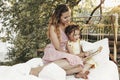 Beautiful mother and child spending time together on sunny terrace near house, mum reads fairy tales loud to lovely girl while Royalty Free Stock Photo