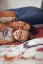 Beautiful mother cuddles with her daughter in bed, giggling and laughing and kissing