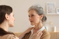 Beautiful mother and daughter. Cheerful young woman is embracing her middle aged mother in living room. Family portrait Royalty Free Stock Photo