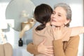 Beautiful mother and daughter. Cheerful young woman is embracing her middle aged mother in living room. Family portrait. Royalty Free Stock Photo